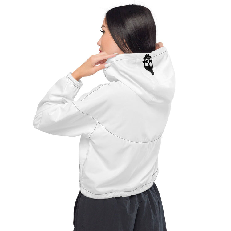 Model wearing white cropped windbreaker with hood up, showing a small black graphic detail on the back, ideal for casual outings.