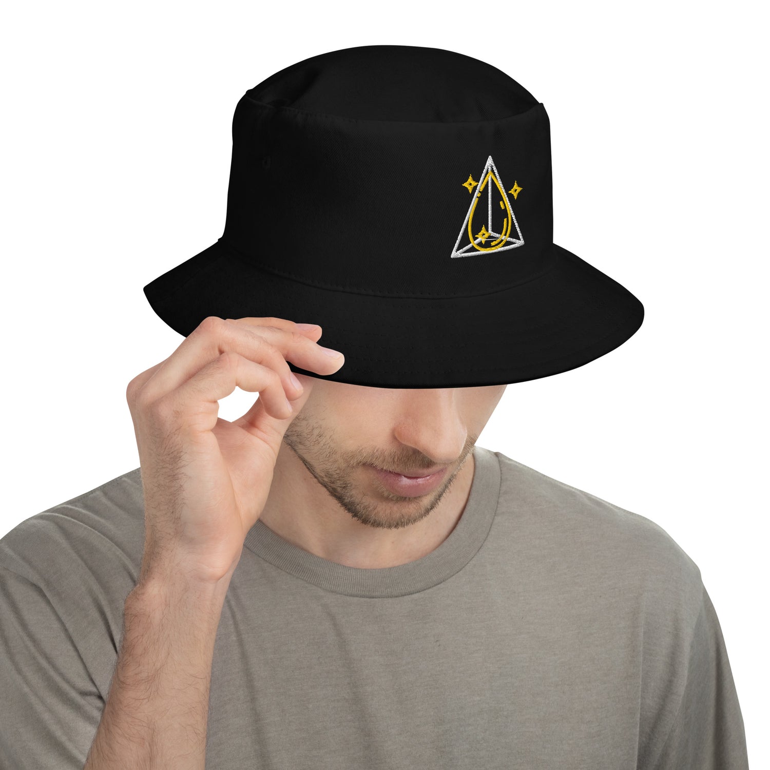 Close-up of a man adjusting a black bucket hat with a geometric prism and star design, highlighting its breathable cotton twill material.