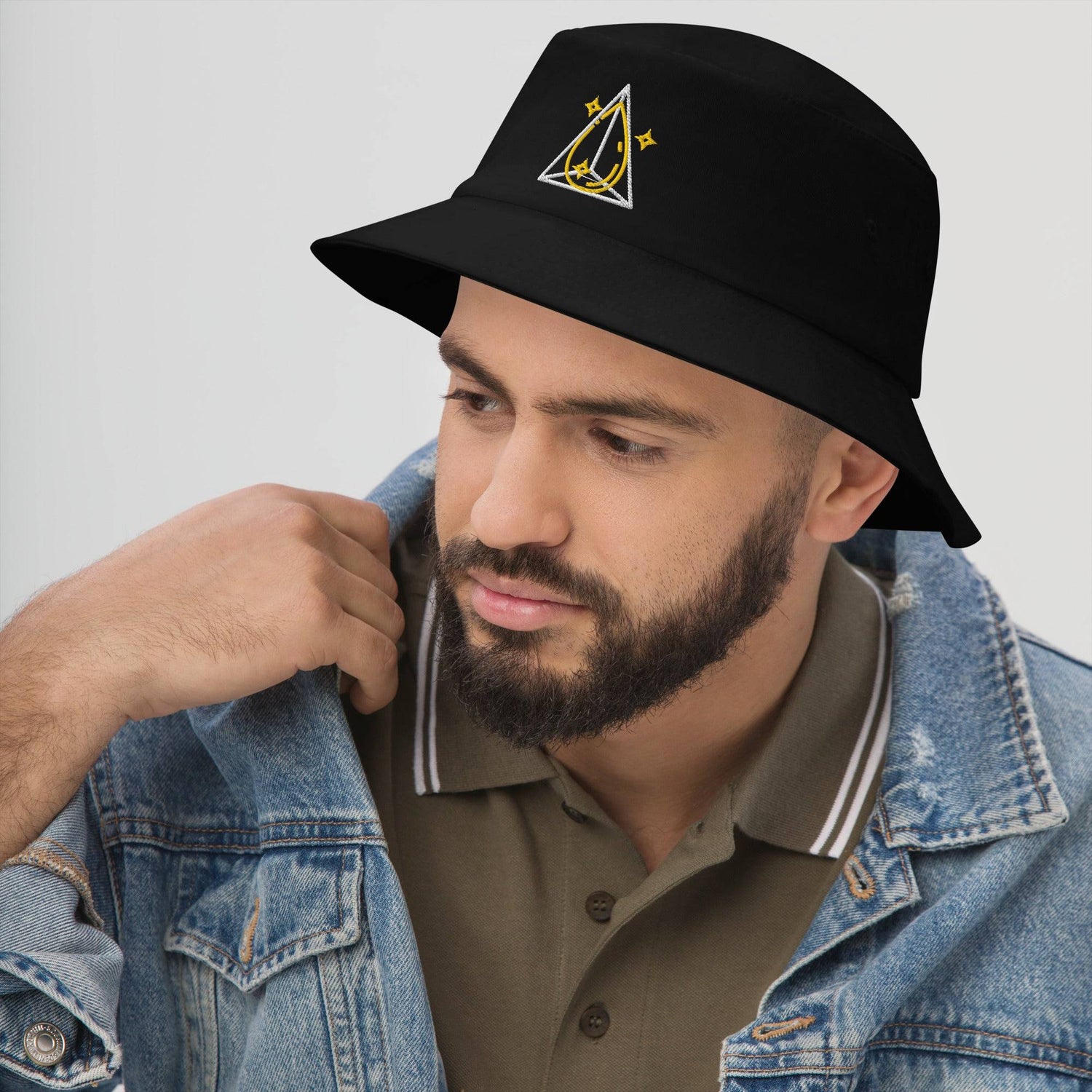 Man in a denim jacket wearing a black bucket hat with a yellow and white prism design, showcasing a stylish and versatile accessory.